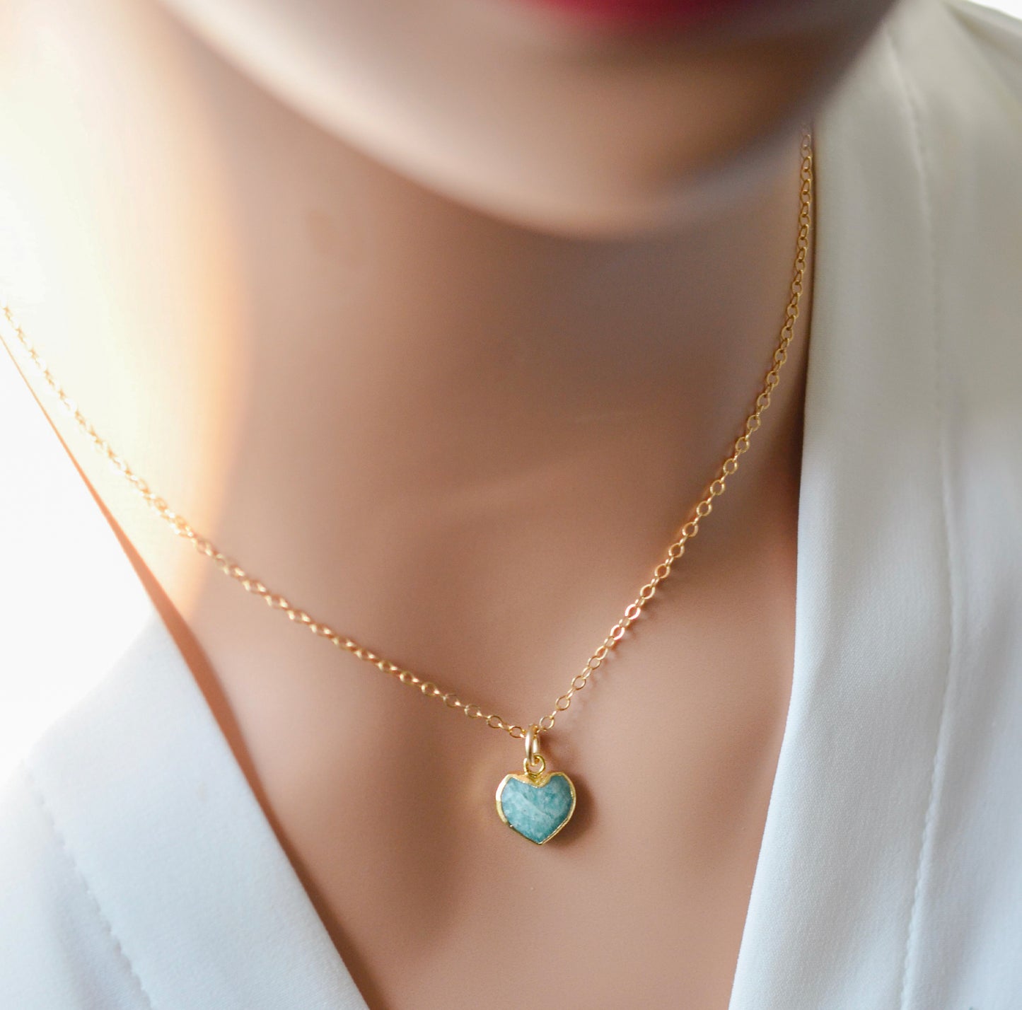 Natural blue green Amazonite gemstone pendant set on a 14k gold filled chain. The stone is a faceted heart shape and bezeled in 22k gold electroplate. Modeled image.