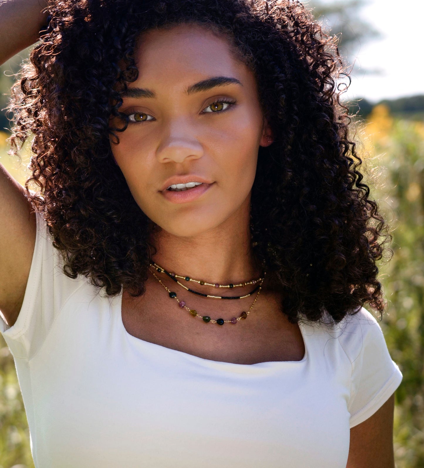 Multi color Tourmaline drops chain necklace. Shown in gold. Stone colors include: pink, green, black, yellow, or brown. Modeled Image. Shown with a beaded tourmaline and black onyx necklace.