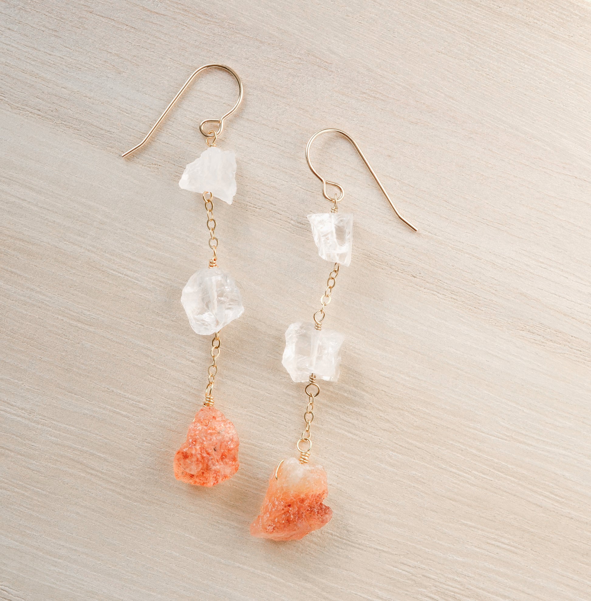 Raw crystal and sunstone earrings. Two clear crystal quartz raw stones are set atop raw, natural sunstone gemstones.