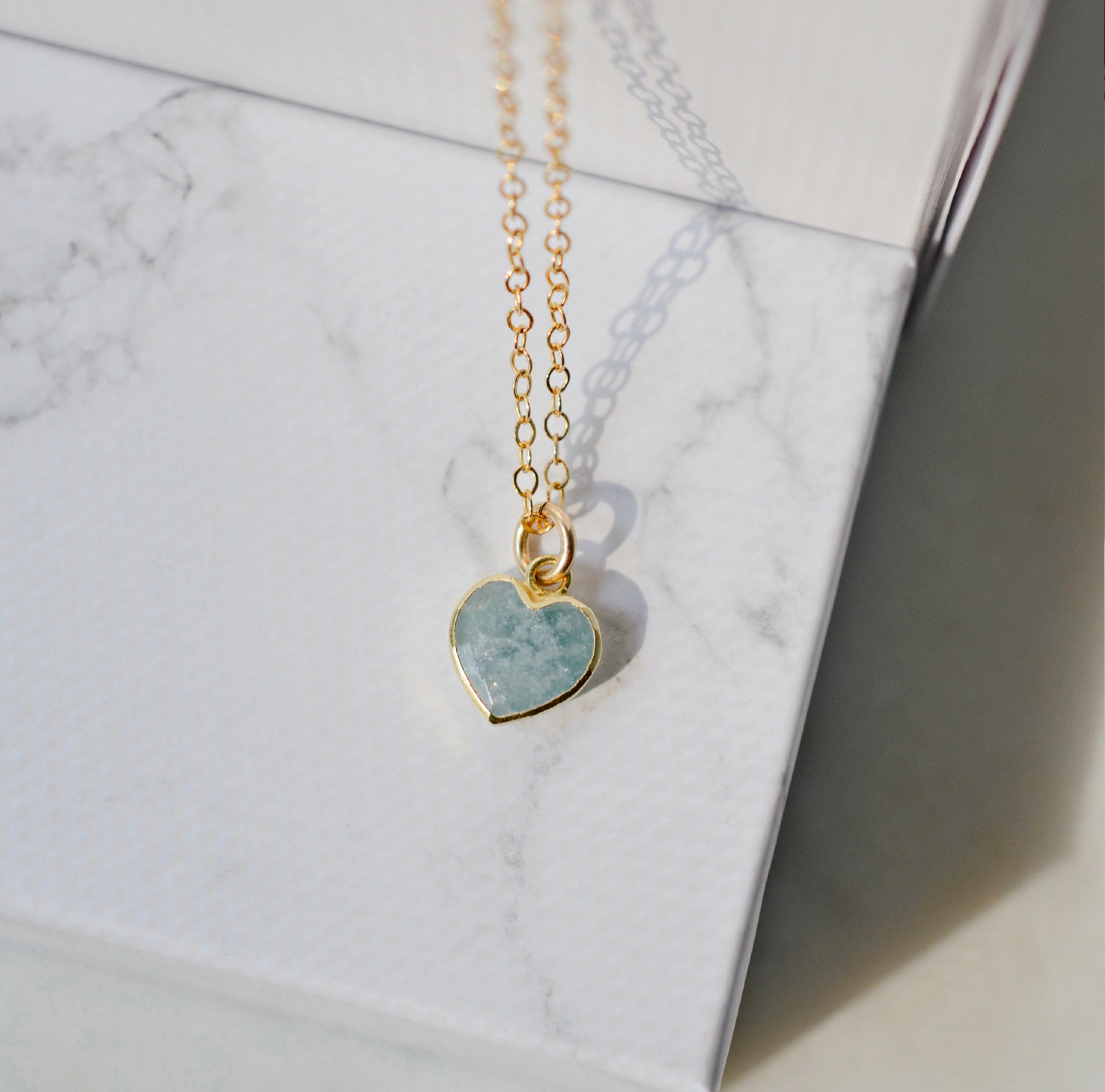 Pale blue natural aquamarine gemstone heart pendant set on a 14k gold filled chain. The stone is genuine and faceted with a 22k gold electroplate bezel.