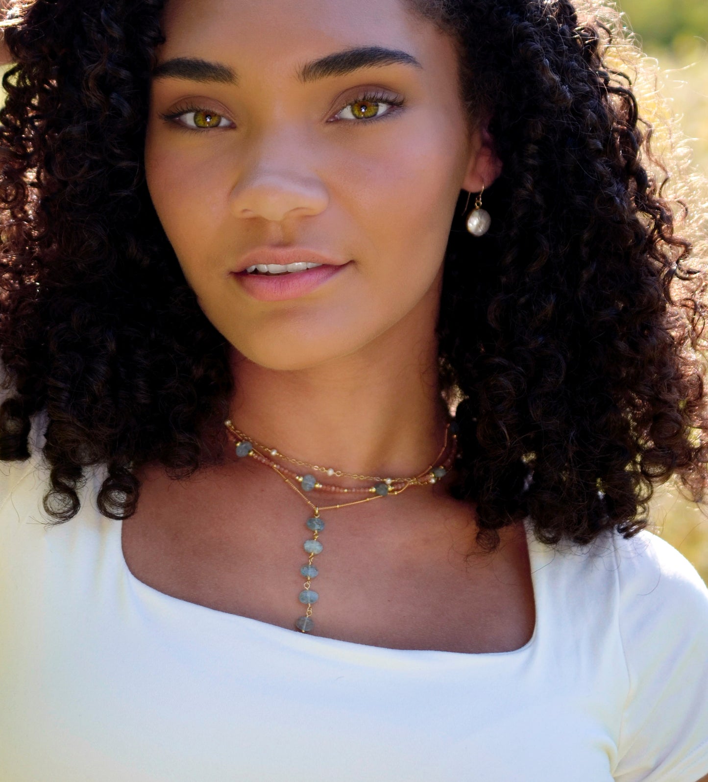White pearl beaded chain necklace modeled with aquamarine necklaces.