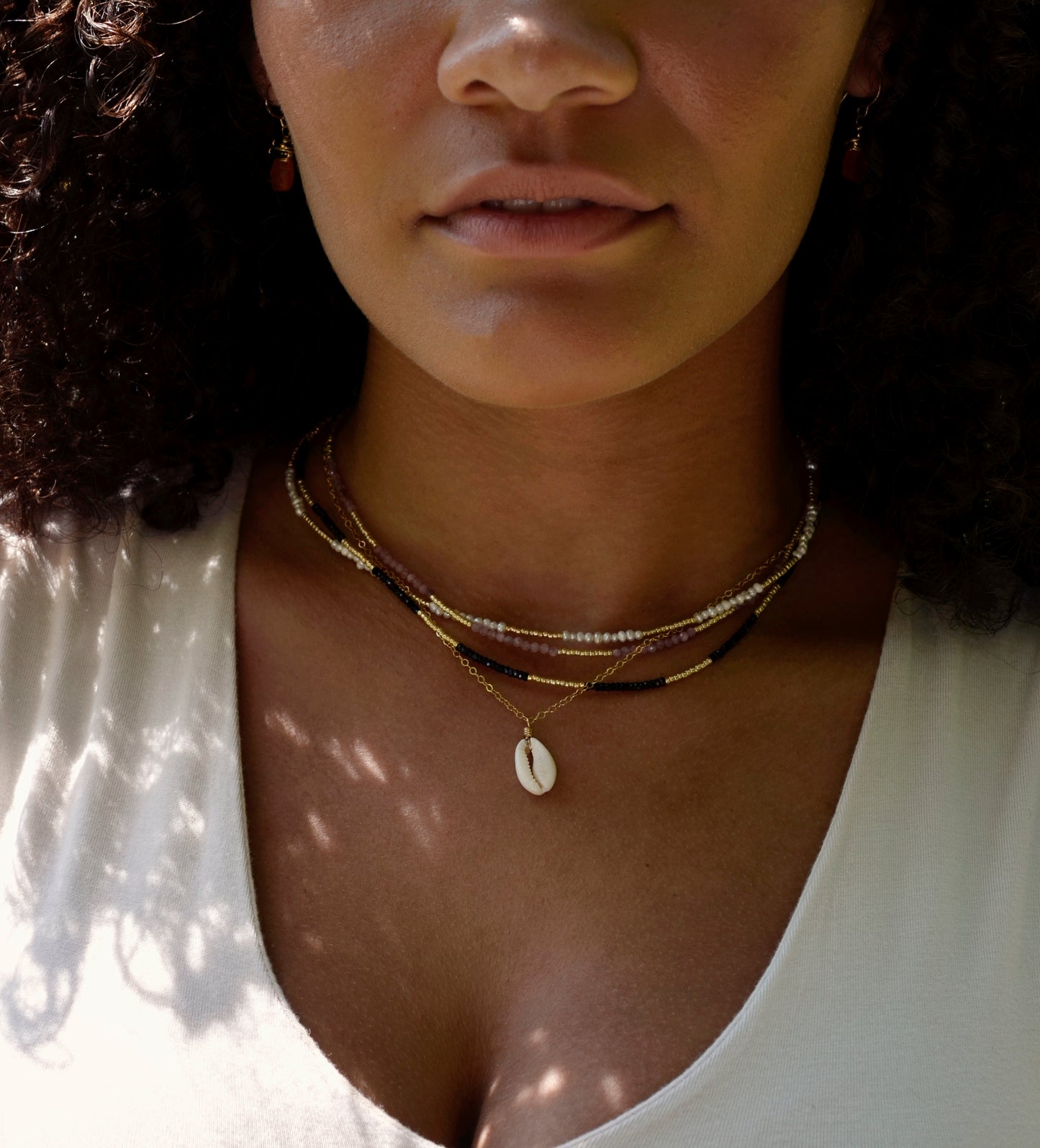 Handmade Cowrie shell necklace modeled with beaded gemstone necklaces.