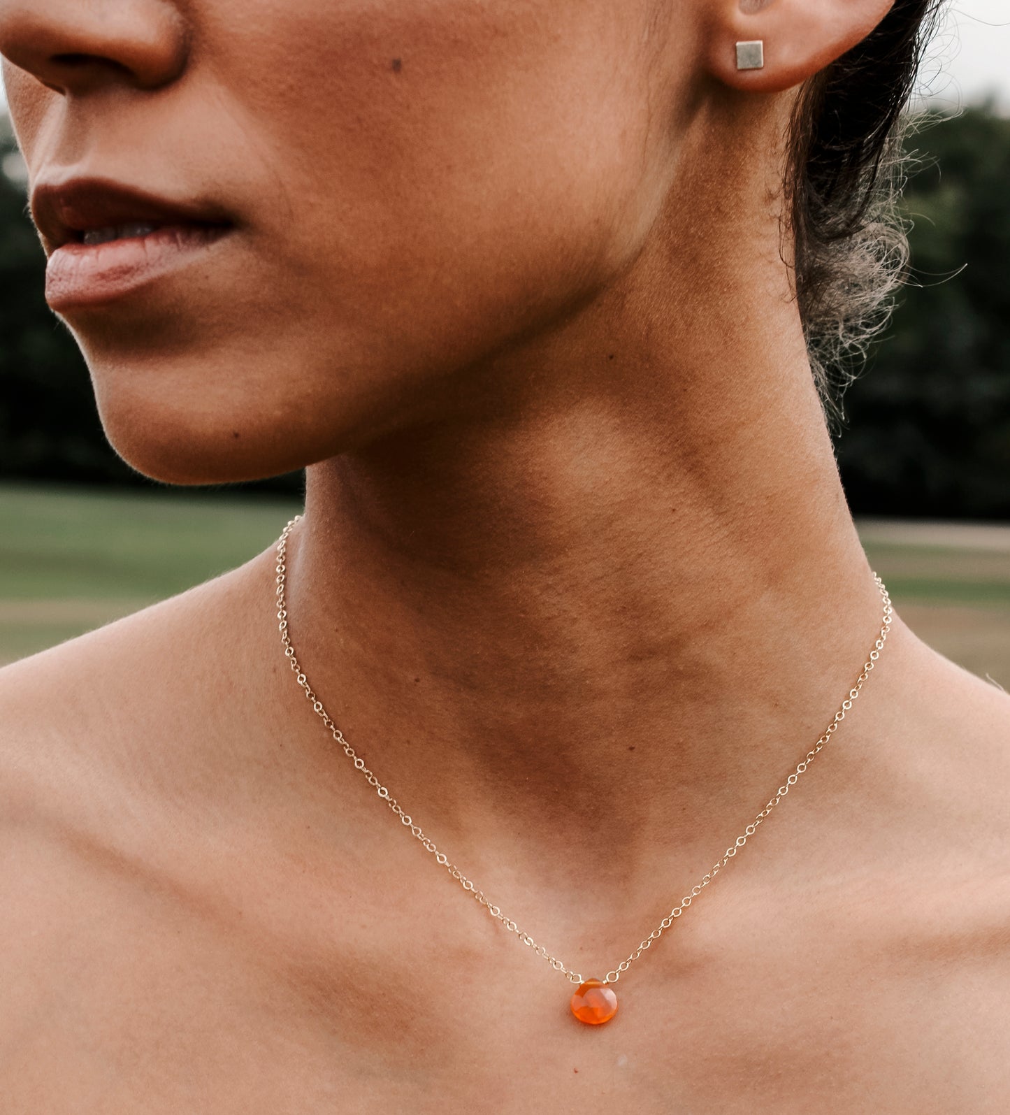 Handmade orange Carnelian Necklace. A single teardrop gemstone placed onto a sterling silver or gold filled chain. Modeled image.