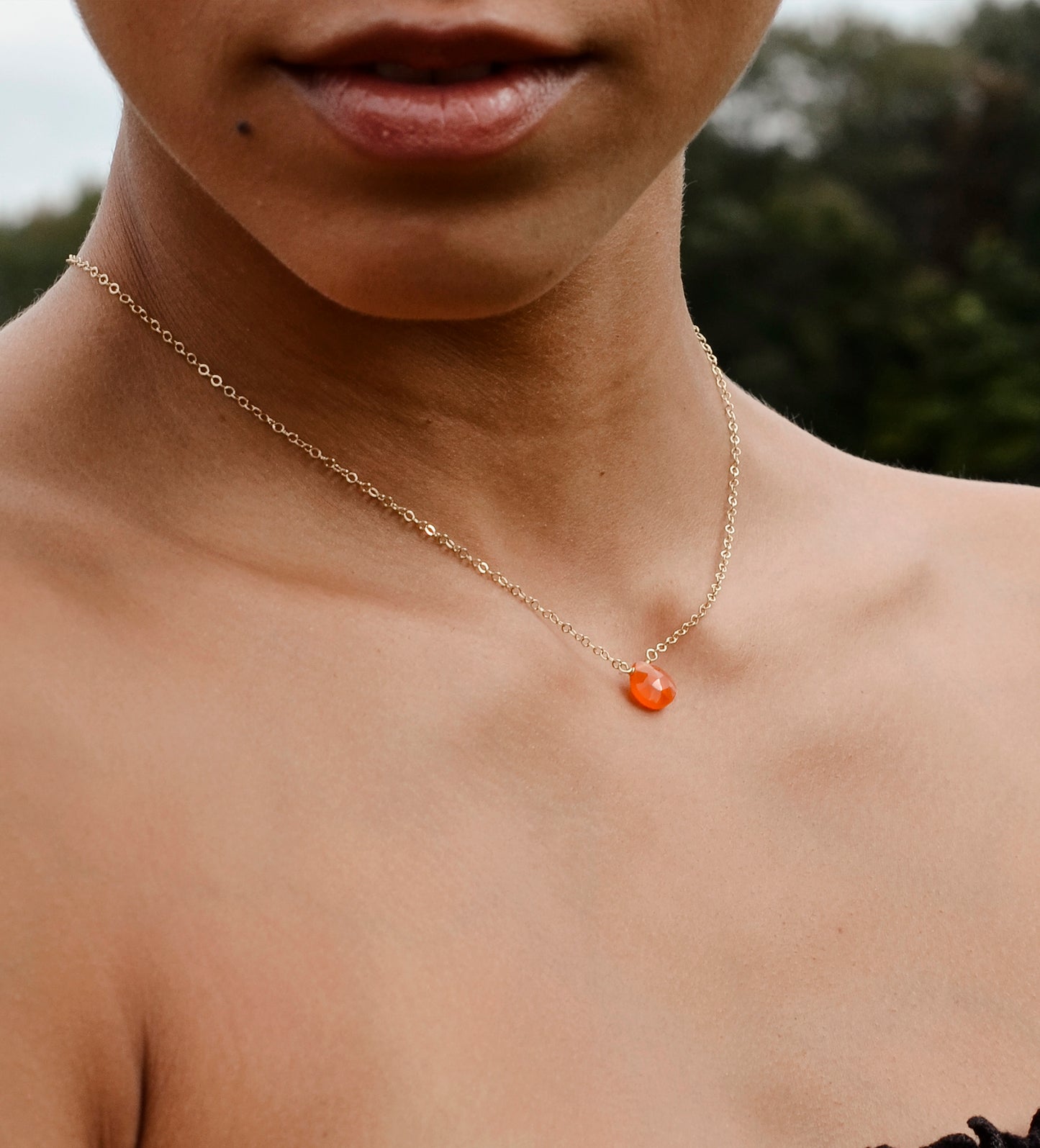 Handmade orange Carnelian Necklace. A single teardrop gemstone placed onto a sterling silver or gold filled chain. Modeled image.