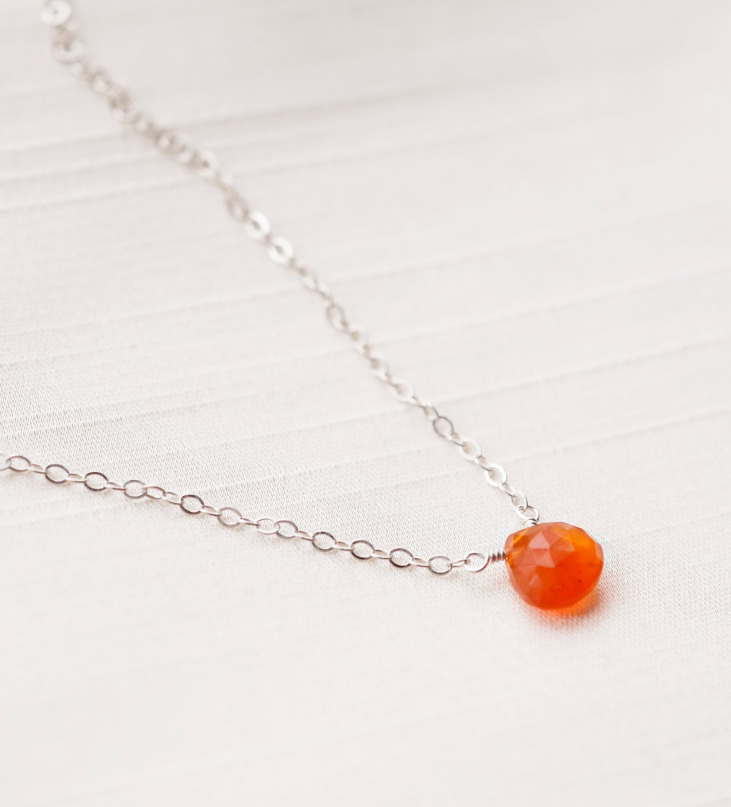 Handmade orange Carnelian Necklace. A single teardrop gemstone placed onto a sterling silver or gold filled chain. Modeled image.