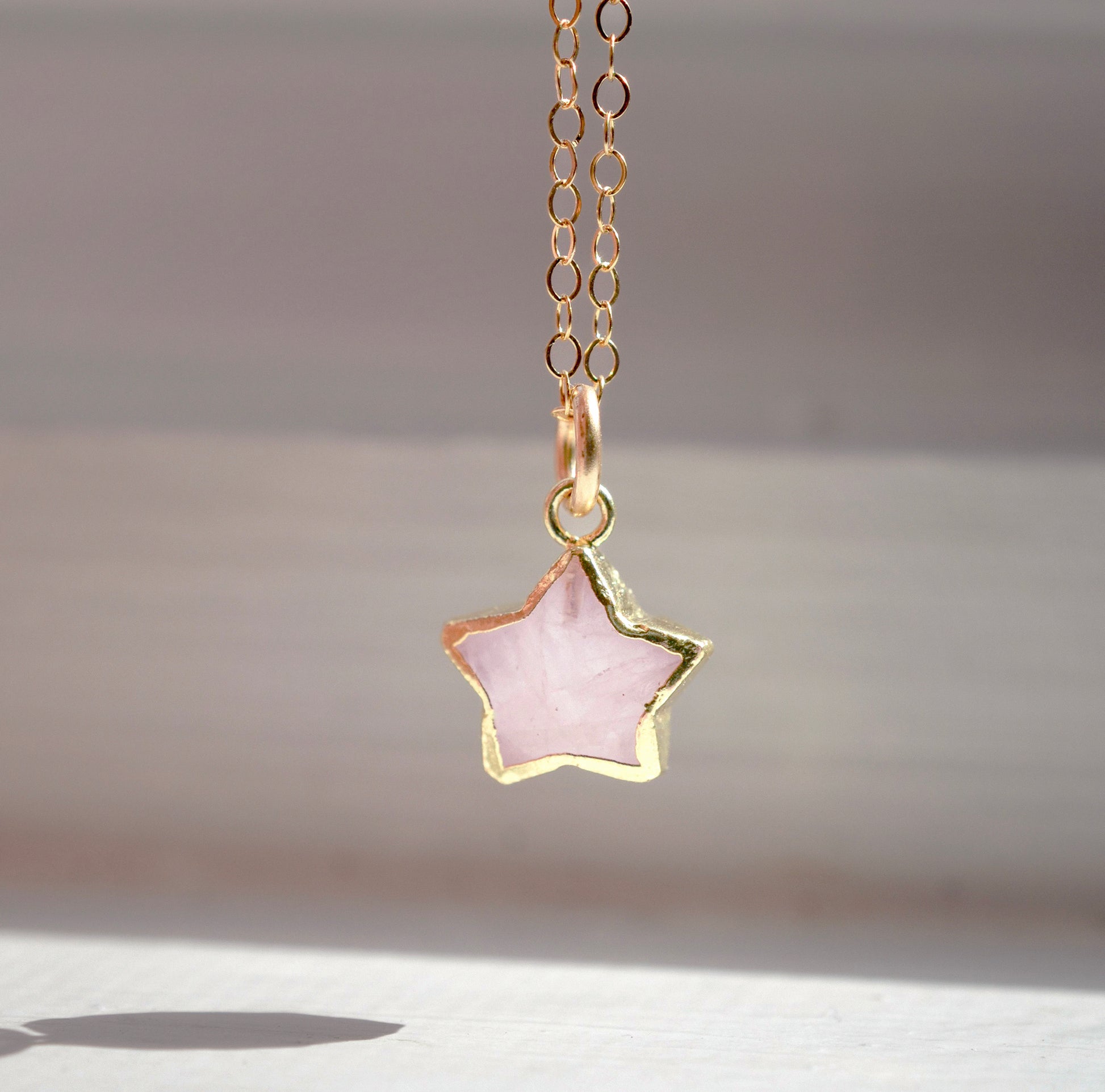 Dainty rose quartz star pendant necklace on a gold chain.