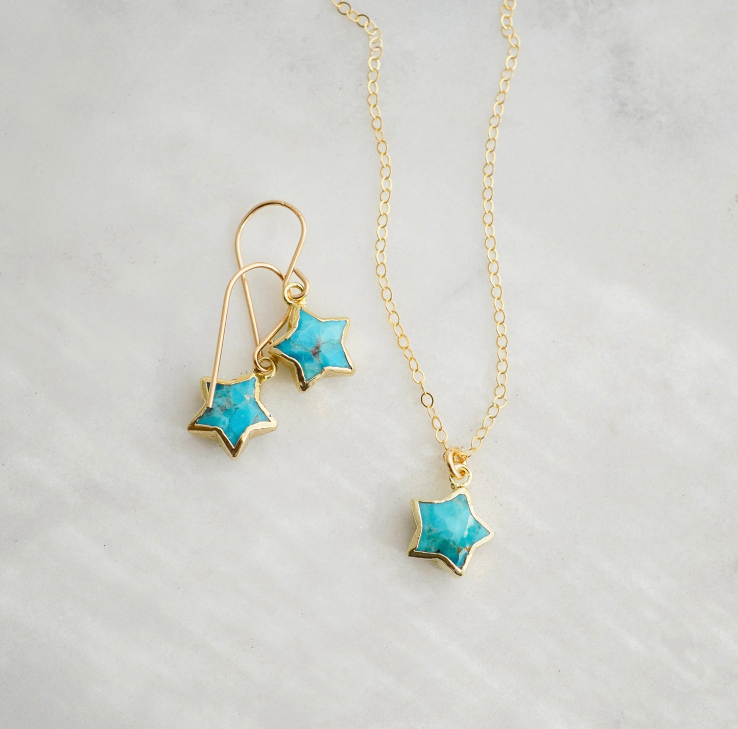 Star-shaped jewelry set with turquoise stones on a light gray background. Handmade celestial jewelry by Gemnia.