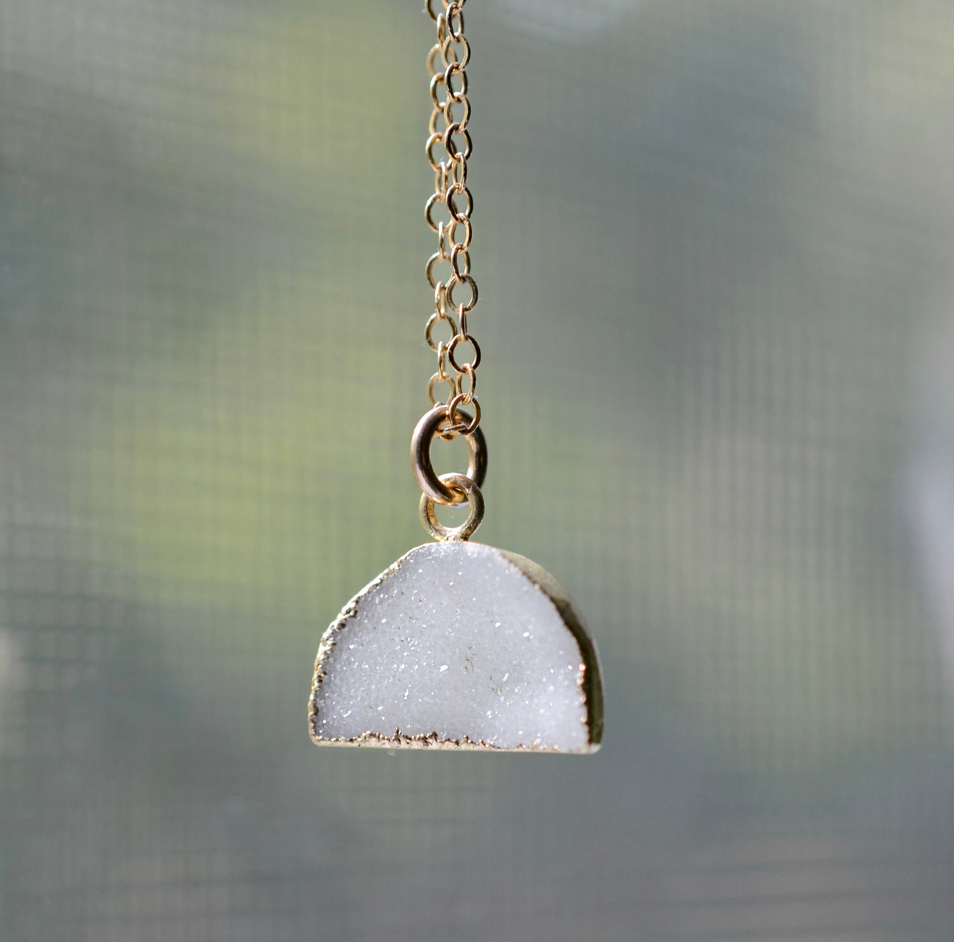 This necklace is handmade with a natural white druzy quartz pendant in a half-circle or crescent shape. Available in 14k gold filled.
