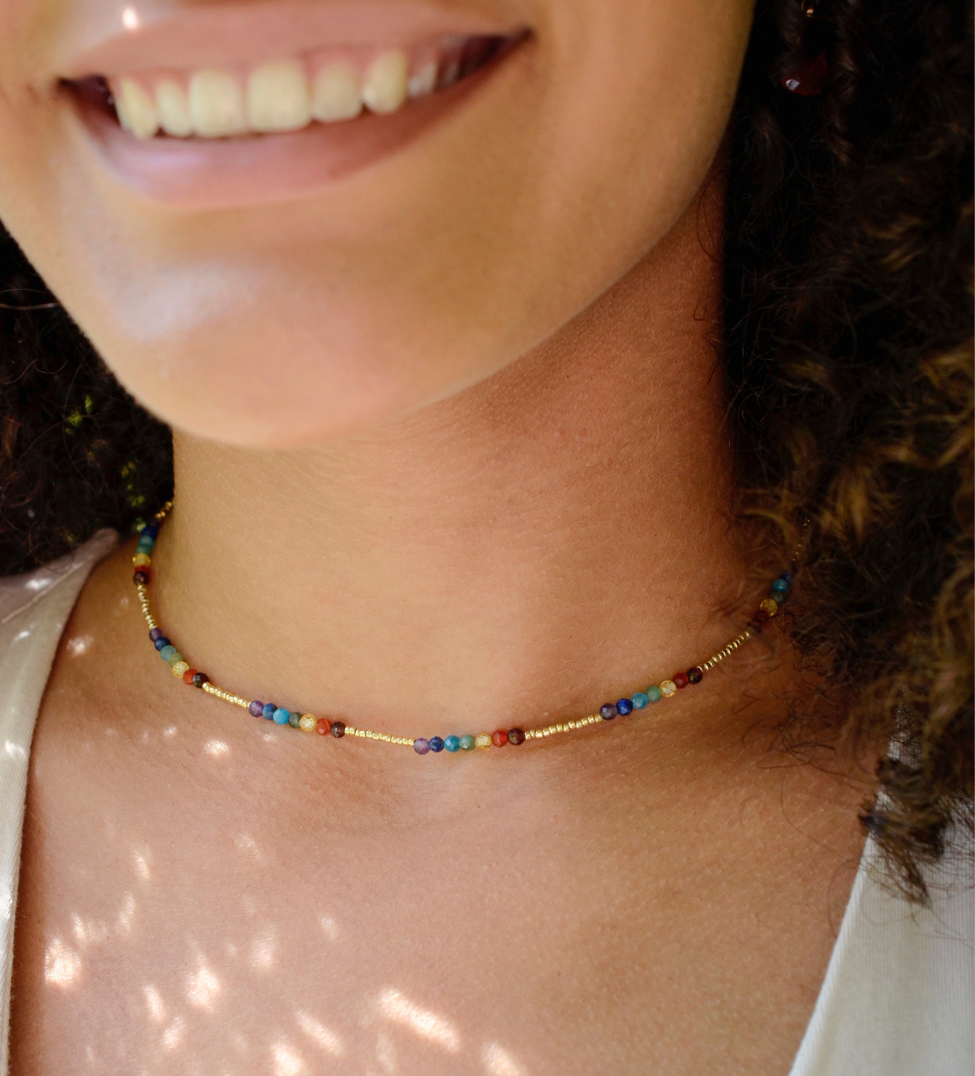 Tiny stones arranged in the order of the seven chakras or rainbow colors. Colors include: purple, blue, aqua, green, yellow, orange, and red. Modeled image.