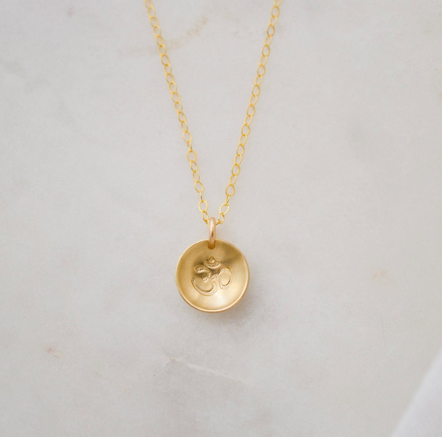 Om symbol stamped into a circle disc and put on a gold filled chain.