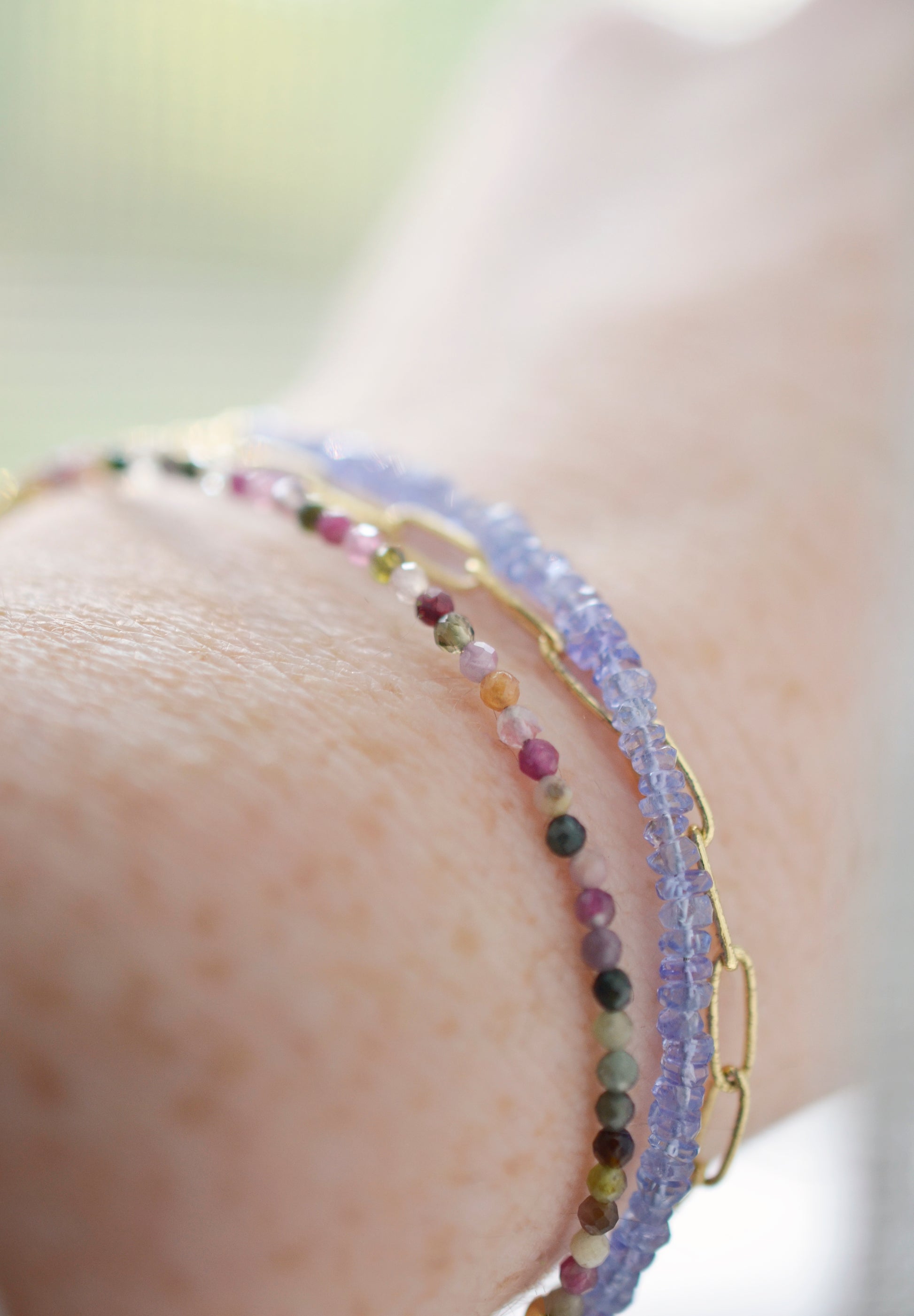 Tiny mulit-color Tourmaline faceted round gemstones on a gold beaded bracelet. Modeled image.