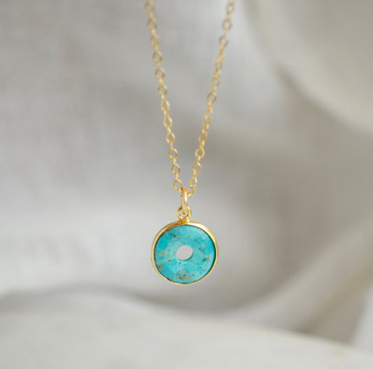 This necklace is handmade with a turquoise stone cut in a doughnut shape then suspended from a 14k gold filled chain. Also available in sterling silver.