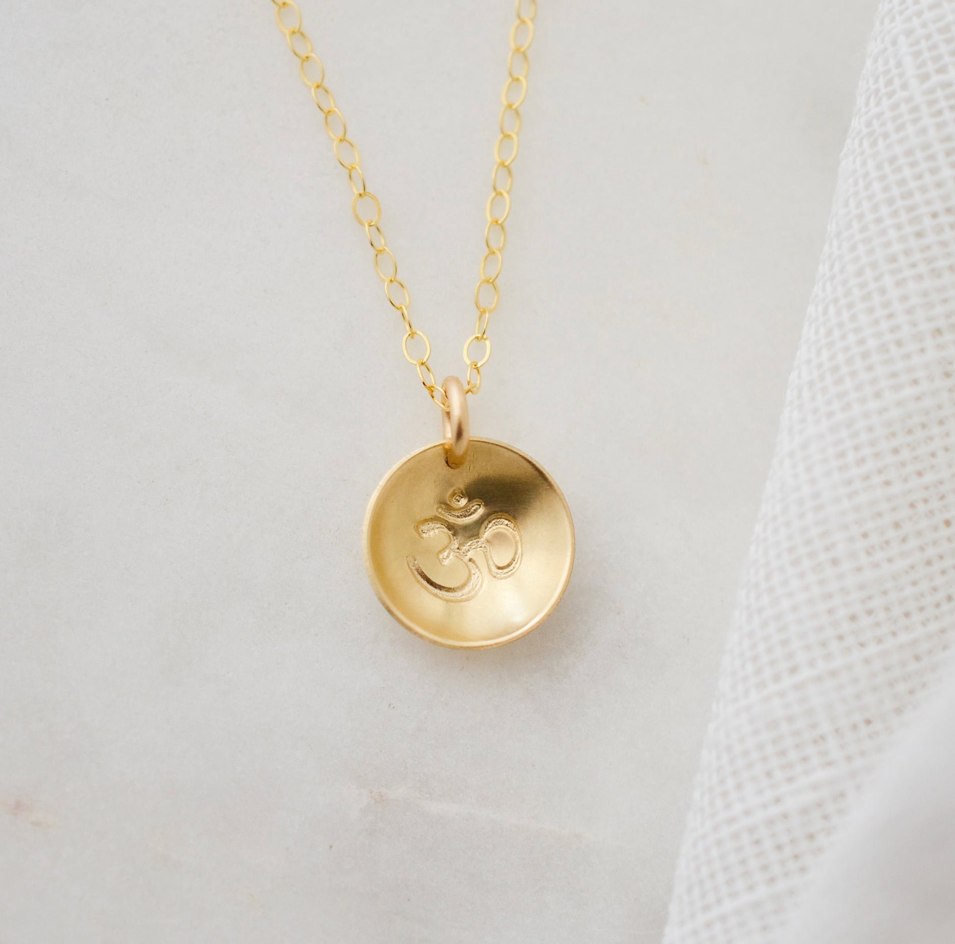 Om symbol stamped into a circle disc and put on a gold filled chain.