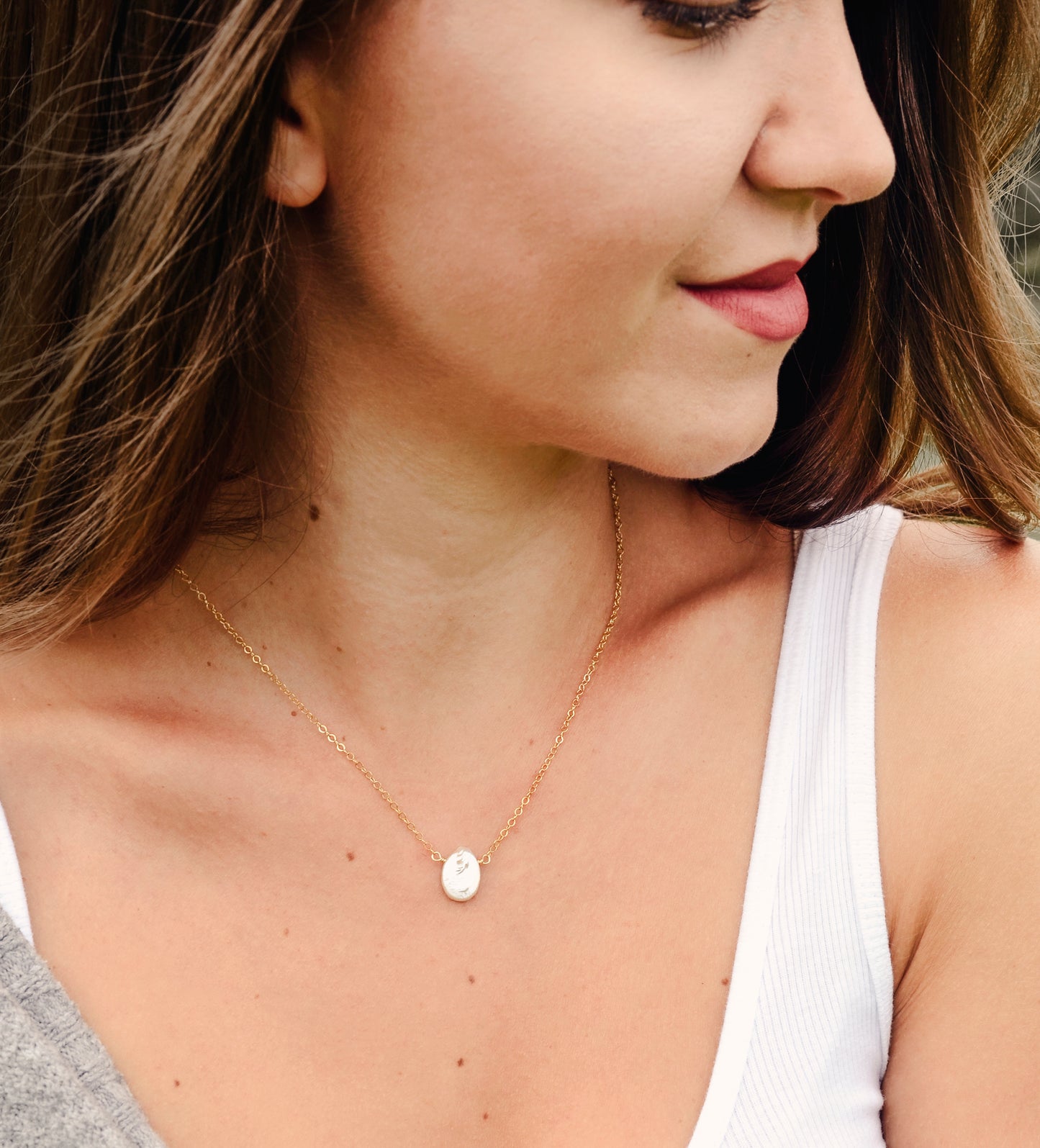 Single white oval shaped freshwater pearl suspended from a sterling silver or 14k gold filled cable chain. Modeled image.