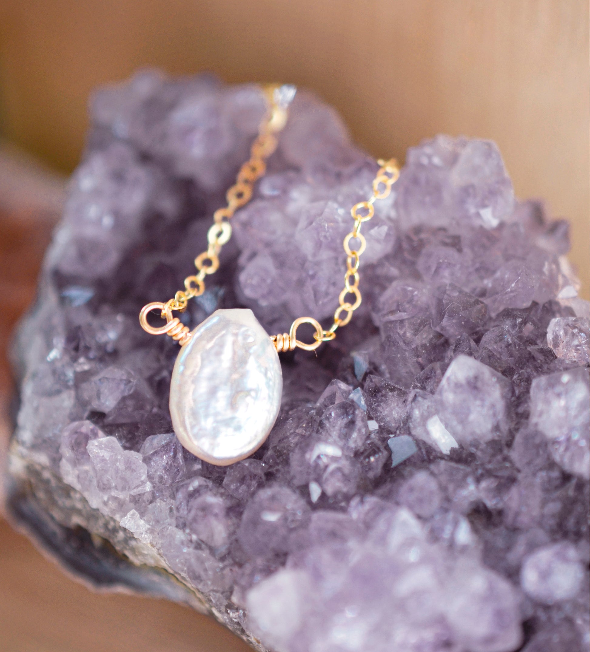 Single white oval shaped freshwater pearl suspended from a 14k gold filled cable chain.