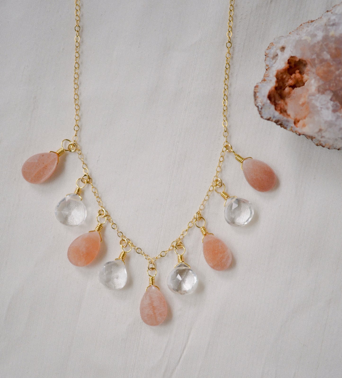 Handmade Necklace. Orange, peach Sunstone and clear Crystal Quartz teardrops dangle off a 14k gold filled chain.