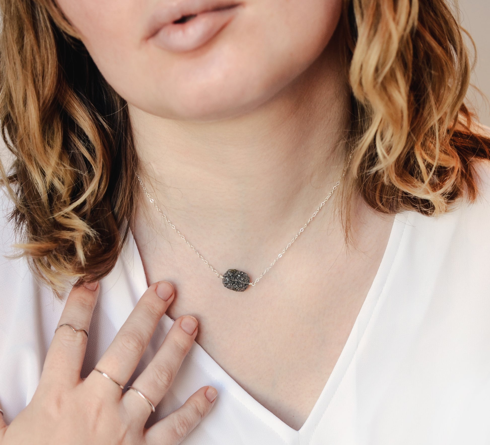 Modeled image of a raw black sunstone gemstone set on a sterling silver chain.