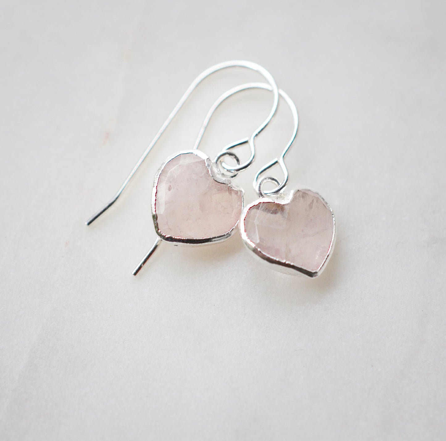 Dainty, handcrafted rose quartz heart earrings featuring a faceted, sparkling heart—the stone of universal love. These gentle dangles, approximately 0.5 inches (12mm/1.2cm) in size, are shown in sterling silver and are also available in 14k gold filled. They make a sweet and thoughtful gift for someone special.