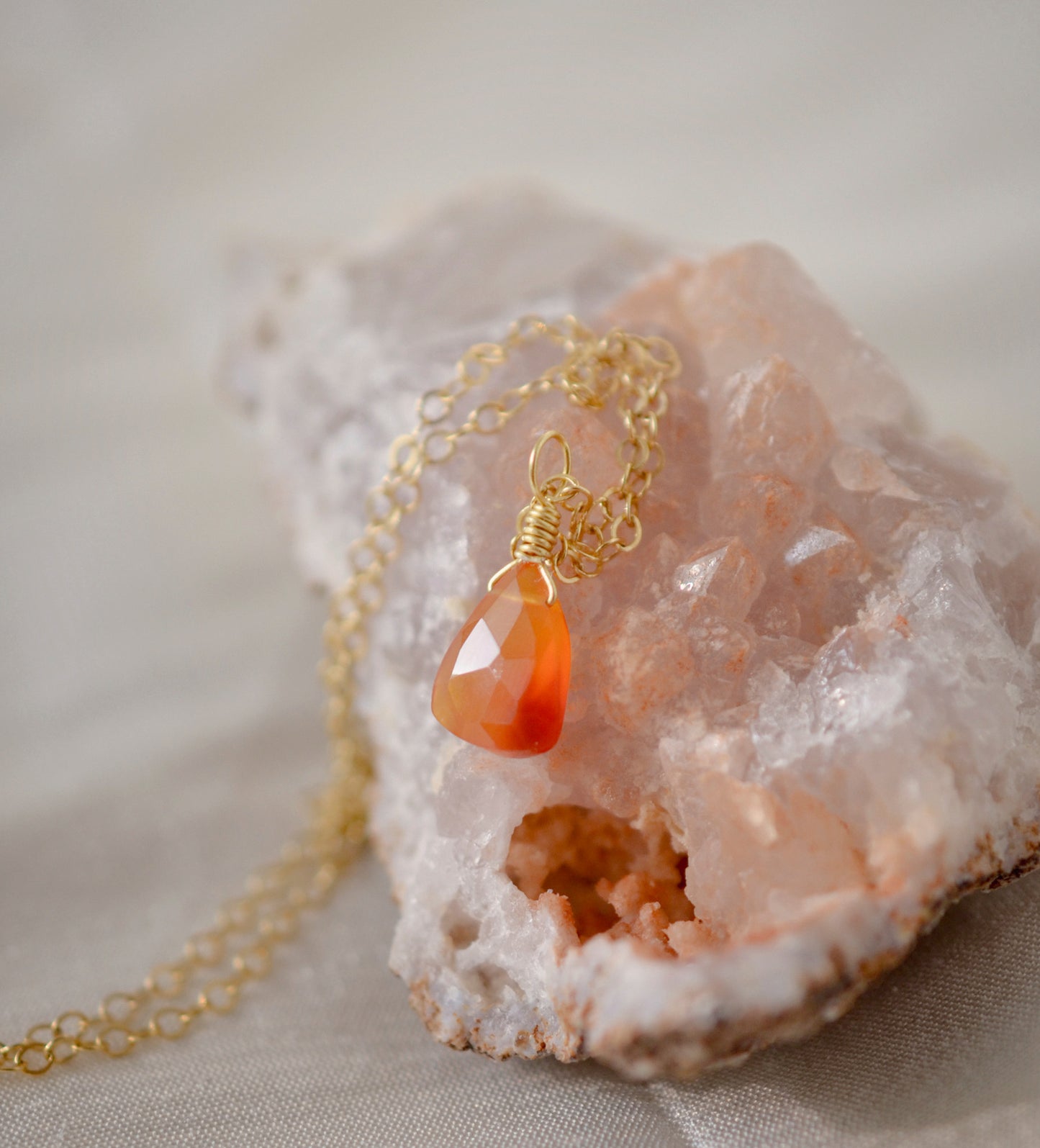 Natural orange triangular shaped Carnelian gemstone set onto a gold chain.