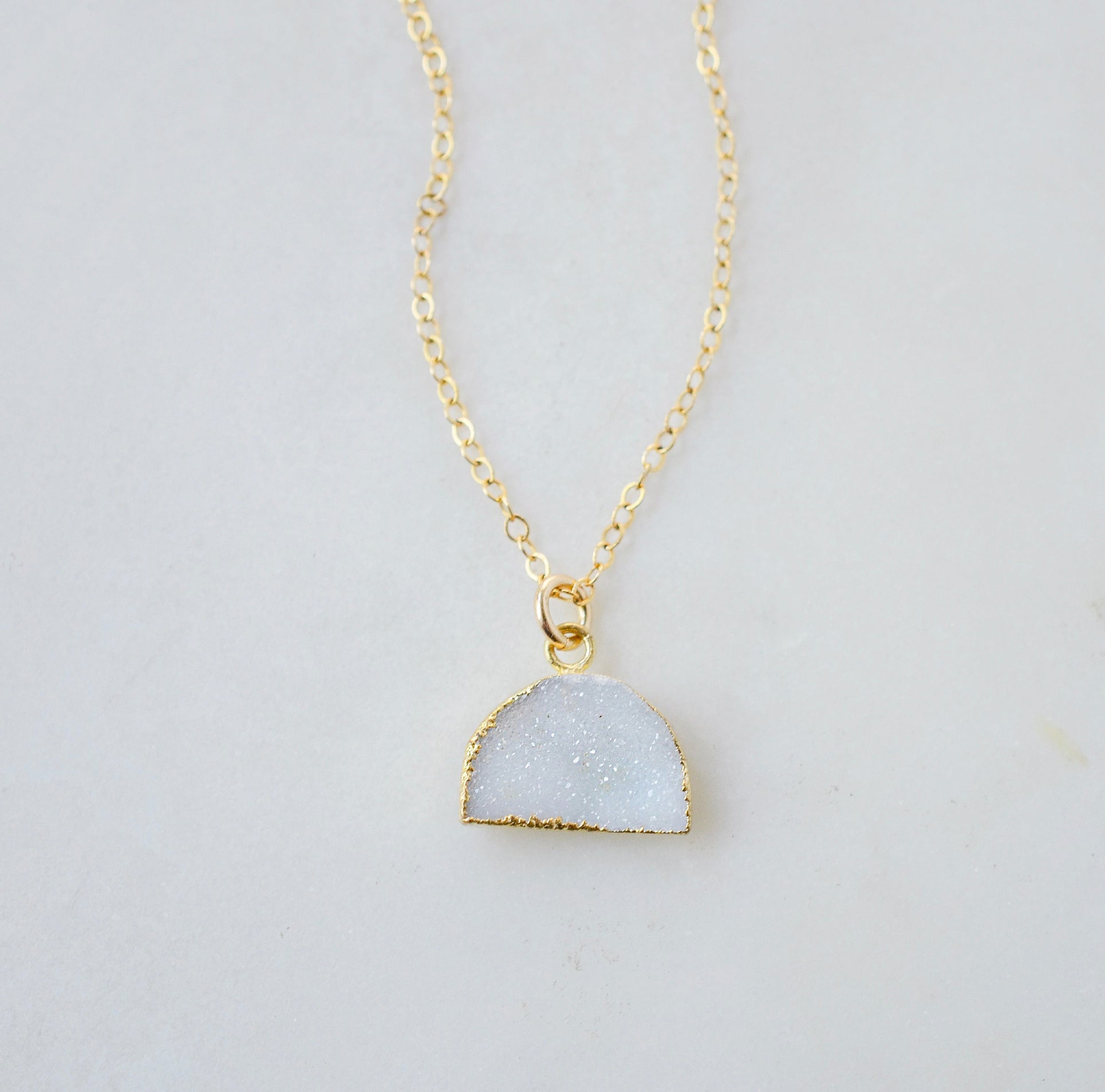 This necklace is handmade with a natural white druzy quartz pendant in a half-circle or crescent shape. Available in 14k gold filled.
