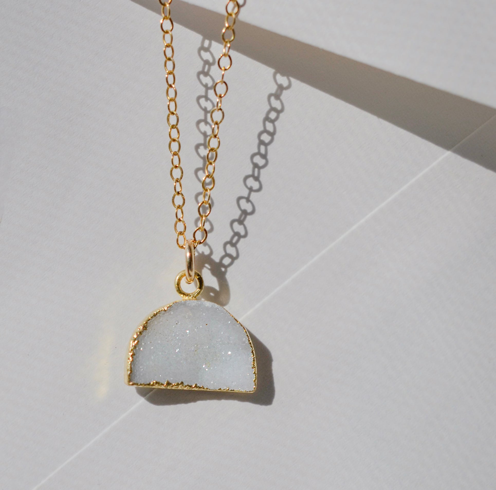 This necklace is handmade with a natural white druzy quartz pendant in a half-circle or crescent shape. Available in 14k gold filled.
