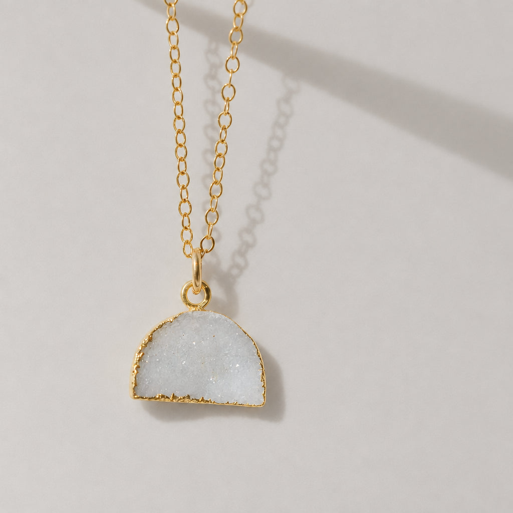 This necklace is handmade with a natural white druzy quartz pendant in a half-circle or crescent shape. Available in 14k gold filled.