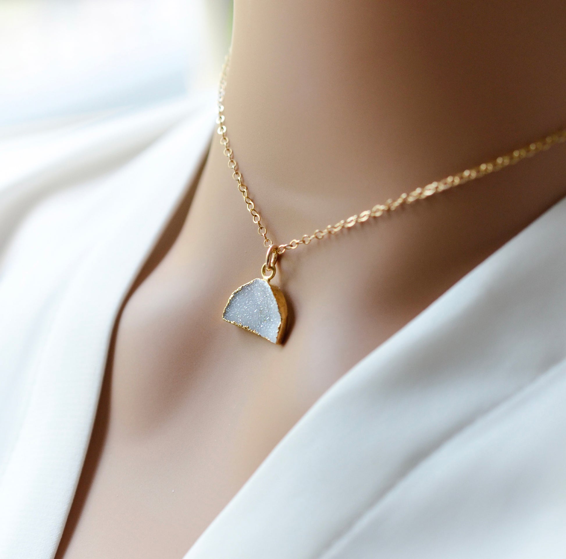This necklace is handmade with a natural white druzy quartz pendant in a half-circle or crescent shape. Available in 14k gold filled. Modeled image.