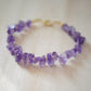 Raw irregular purple amethyst gemstones strung together with tiny gold beads in between each stone. 