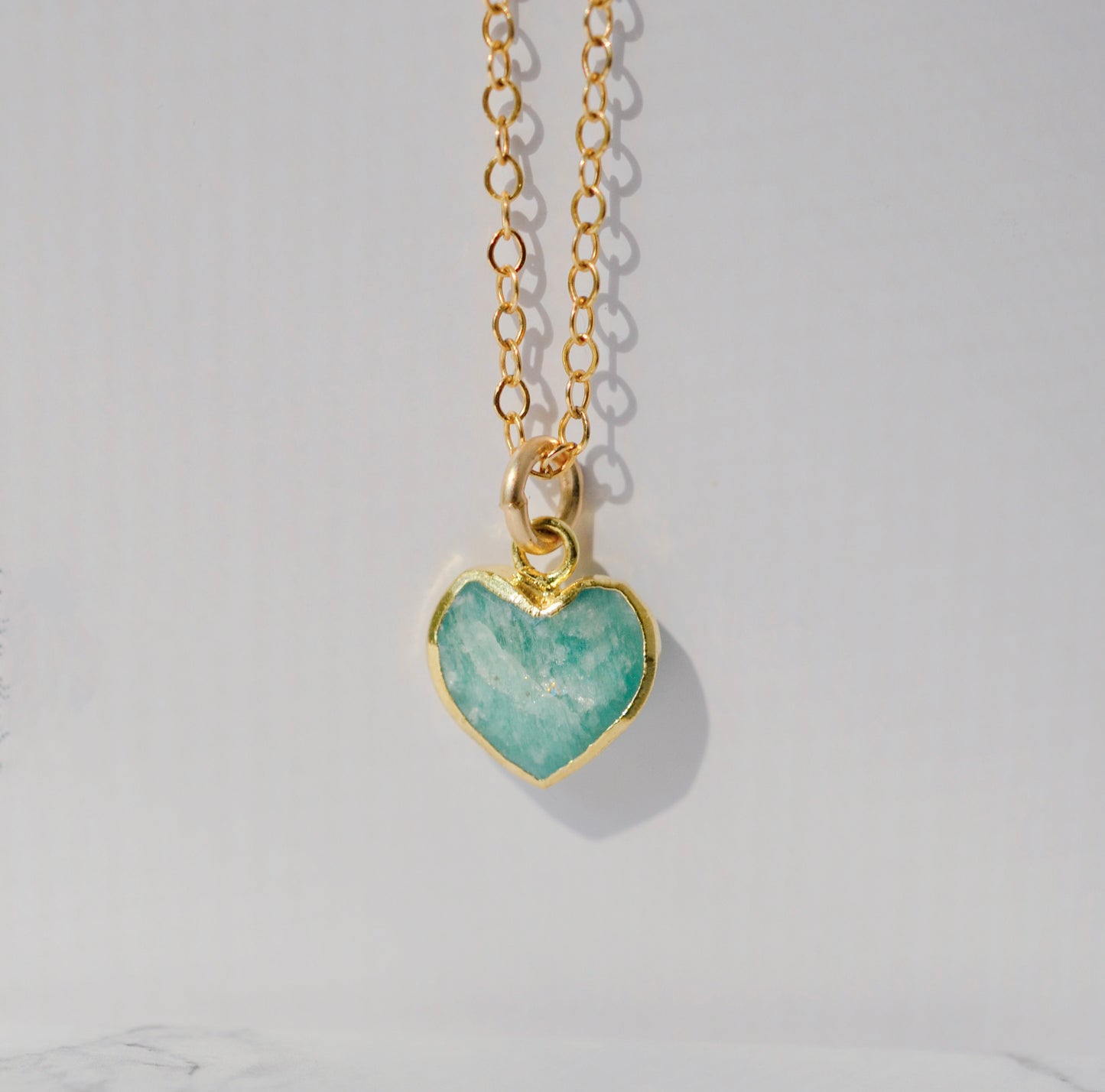 Natural blue green Amazonite gemstone pendant set on a 14k gold filled chain. The stone is a faceted heart shape and bezeled in 22k gold electroplate.