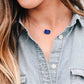 Natural blue lapis lazuli slice set onto a sterling silver chain. The stone is smooth polished with raw edges and oval in shape. Natural pyrite and calcite flecks are visible within each stone. Modeled image.