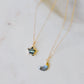 Two delicate gold chain necklaces with star and crescent moon pendants featuring natural labradorite gemstones, displayed on a light marble surface. Each necklace is handmade by Gemnia in Connecticut.