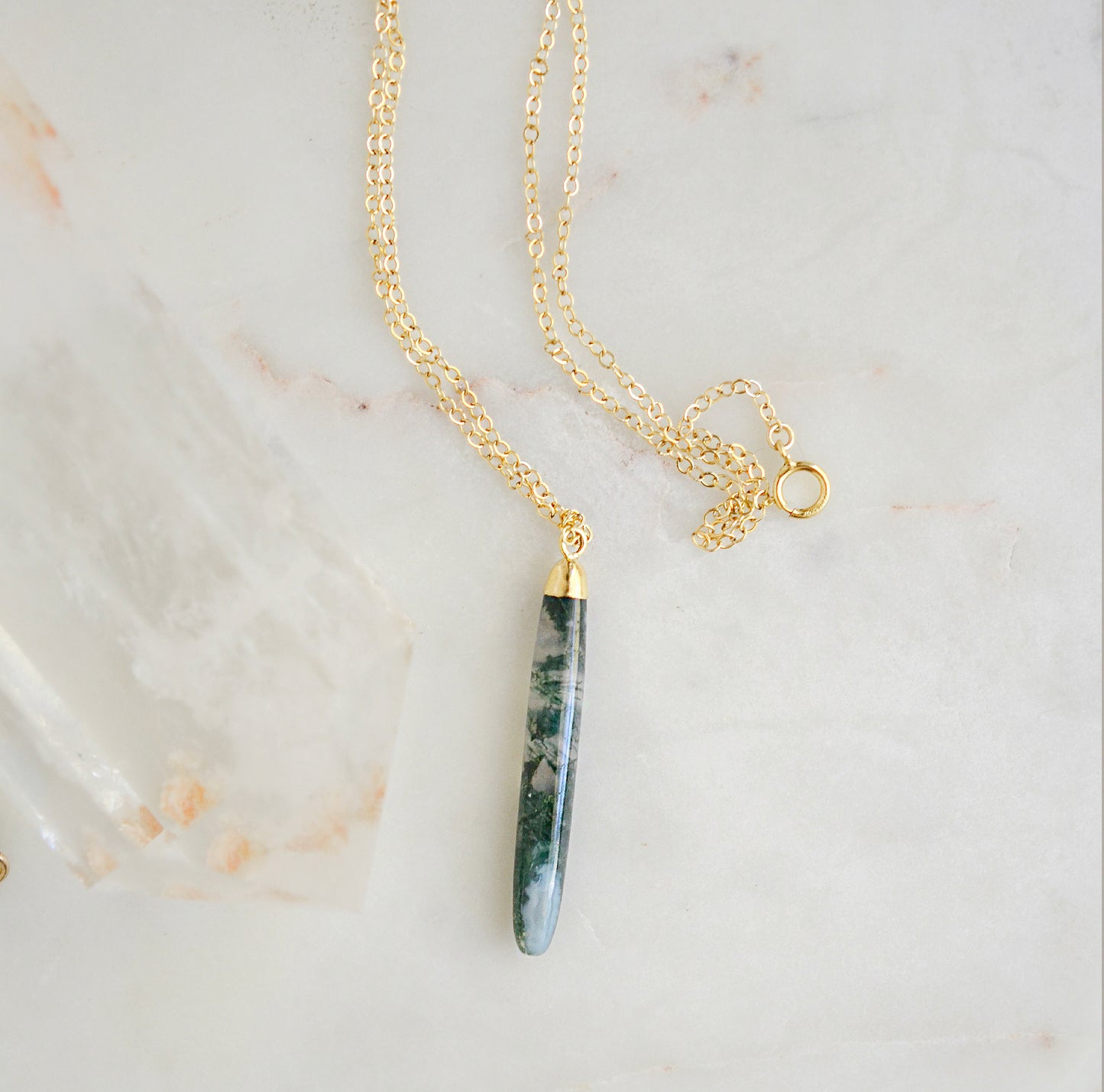 Long green, white, and clear real natural moss agate stone set on a 14k gold filled chain. The pendant is a long thin oval shape.