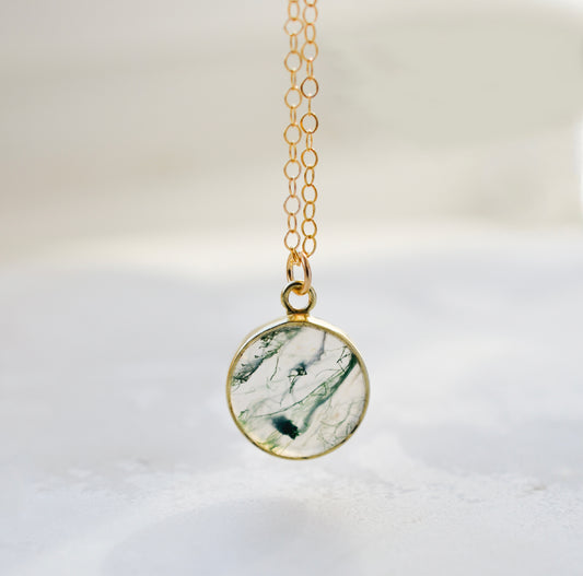 A genuine, natural moss agate circle shaped pendant set on a 14k gold filled chain. This minimalist, dainty, smooth polished pendant is handmade in Connecticut by Gemnia Jewelry.