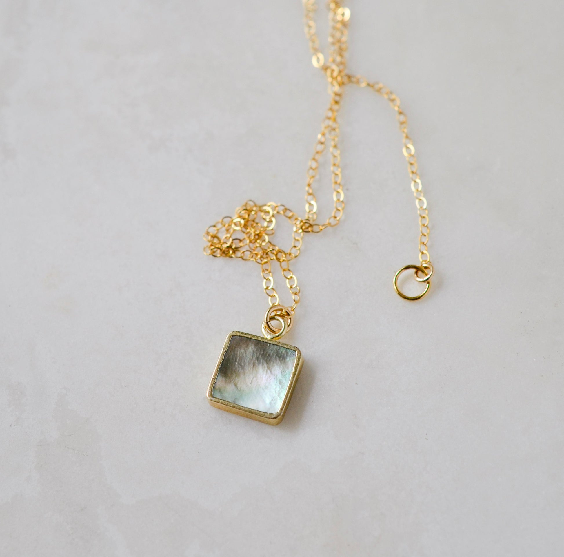 A natural silver colored mother of pearl square dainty shaped pendant set on a 14k gold filled chain. This necklace is handmade in Connecticut by Gemnia.