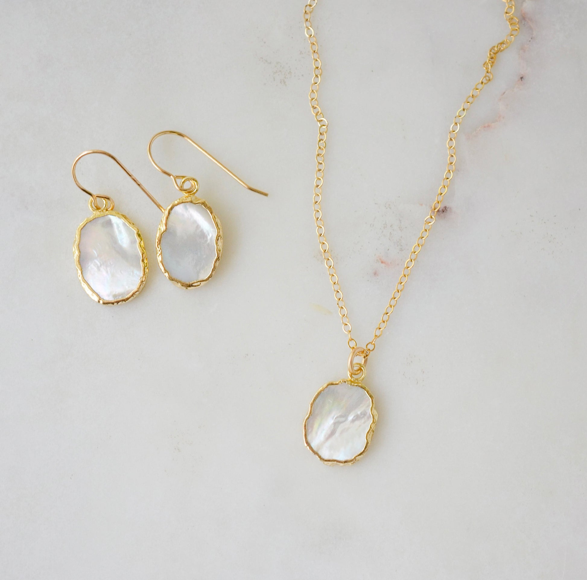 A matching set of mother of pearl earrings and necklace shown in gold. Handmade in Connecticut by Gemnia.