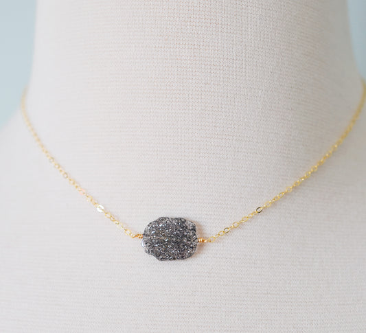 Genuine raw black sunstone gemstone set on a gold filled chain. The shape of the stone is irregular.