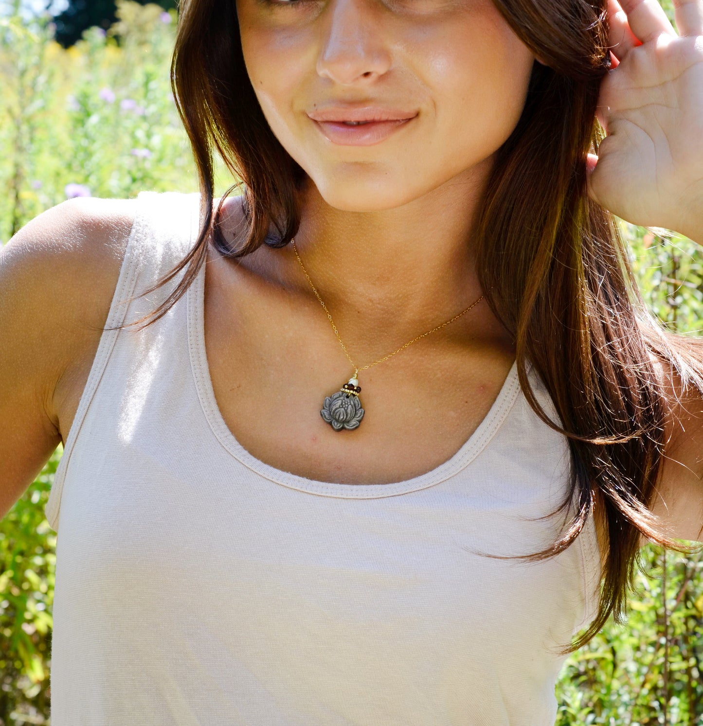 Modeled image: A handmade gemstone pendant featuring a carved obsidian lotus. Garnet, pearl, and gold beads decorate its top. The chain is 14k gold filled.