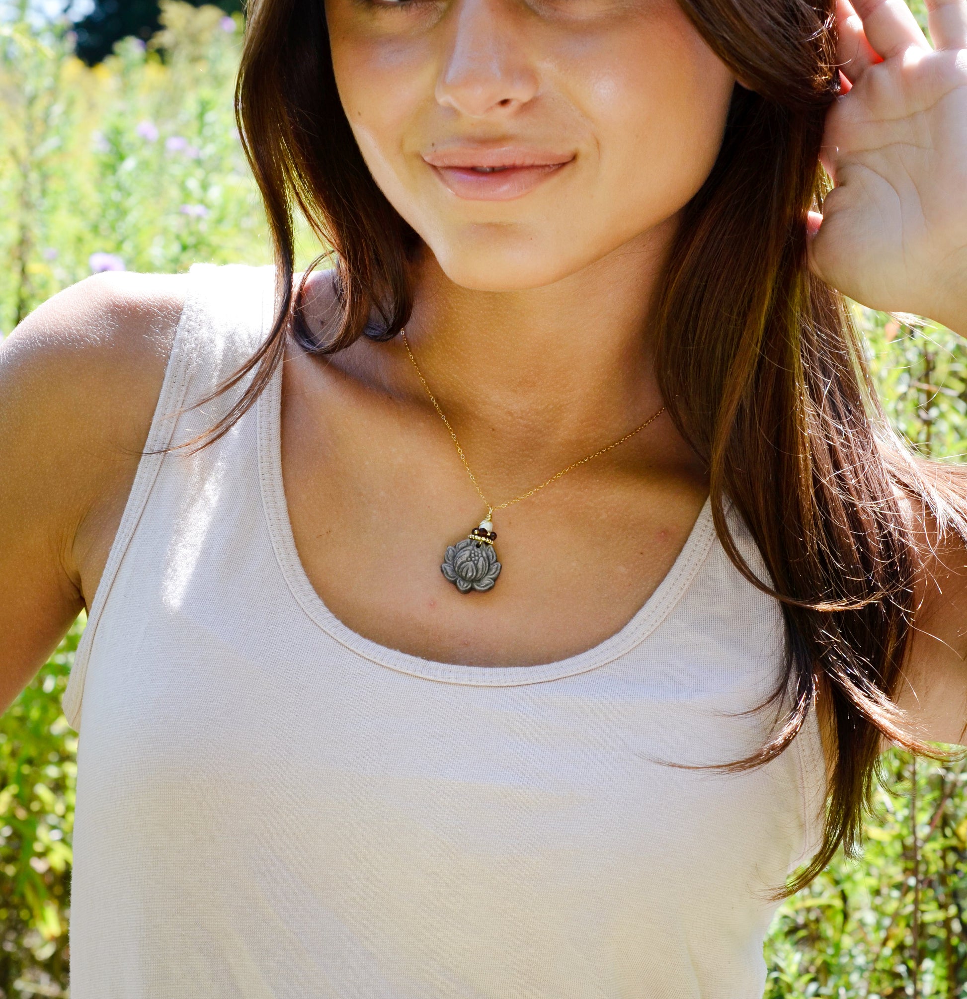 Modeled image: A handmade gemstone pendant featuring a carved obsidian lotus. Garnet, pearl, and gold beads decorate its top. The chain is 14k gold filled.