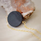 Matte black Onyx circle pendant suspended from a 14k gold filled chain. The stone has a smooth matte finish. 