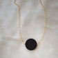 Matte black Onyx circle pendant suspended from a 14k gold filled chain. The stone has a smooth matte finish. 