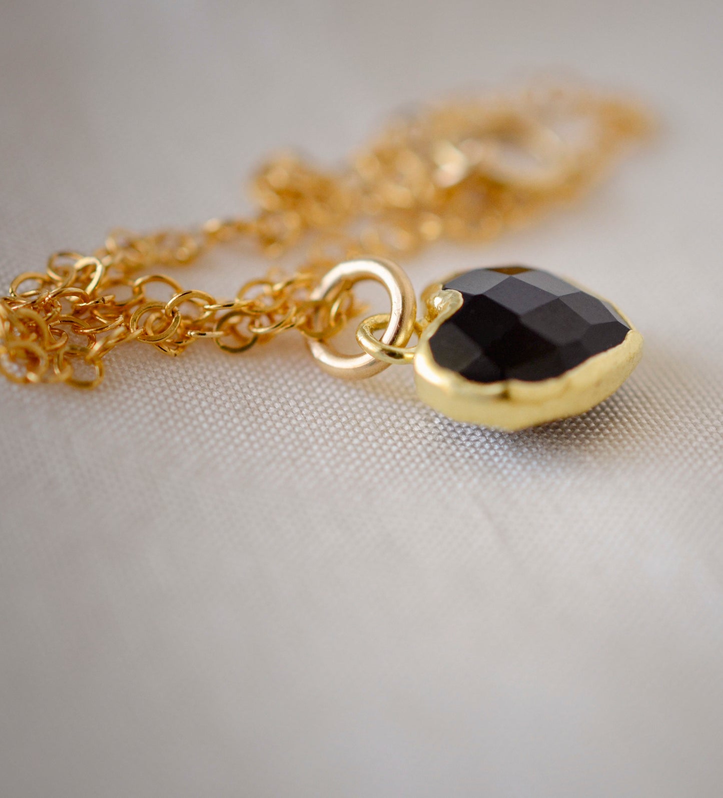 Black Onyx gold heart necklace. A black stone heart bezeled in gold is suspended from a 14k gold filled chain.
