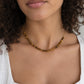 A woman wearing a beaded tiger eye stone necklace in gold. The gemstones are natural and genuine smooth polished. Jewelry is handmade in Connecticut by Gemnia.
