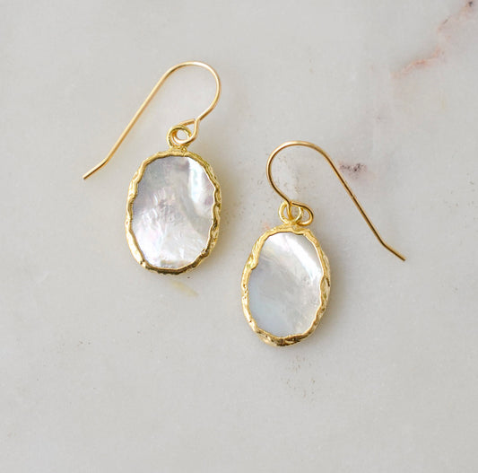 A pair of natural oval mother of pearl earrings dipped in 24k gold and set on 14k gold filled earwires. The shells are smooth polished and flash shades of white and silver.