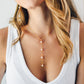 Modeled image. Four semi-round white freshwater pearls are suspended in a Y-style necklace on a 14k gold filled chain. Each pearl is approximately one inch apart.