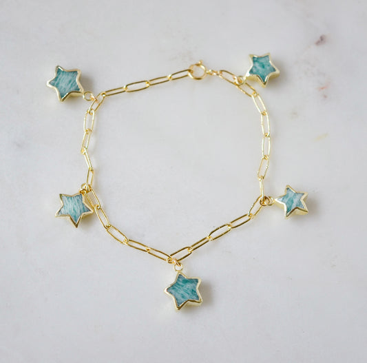 Gold bracelet with blue amazonite star-shaped gemstone charms on a light gray background.