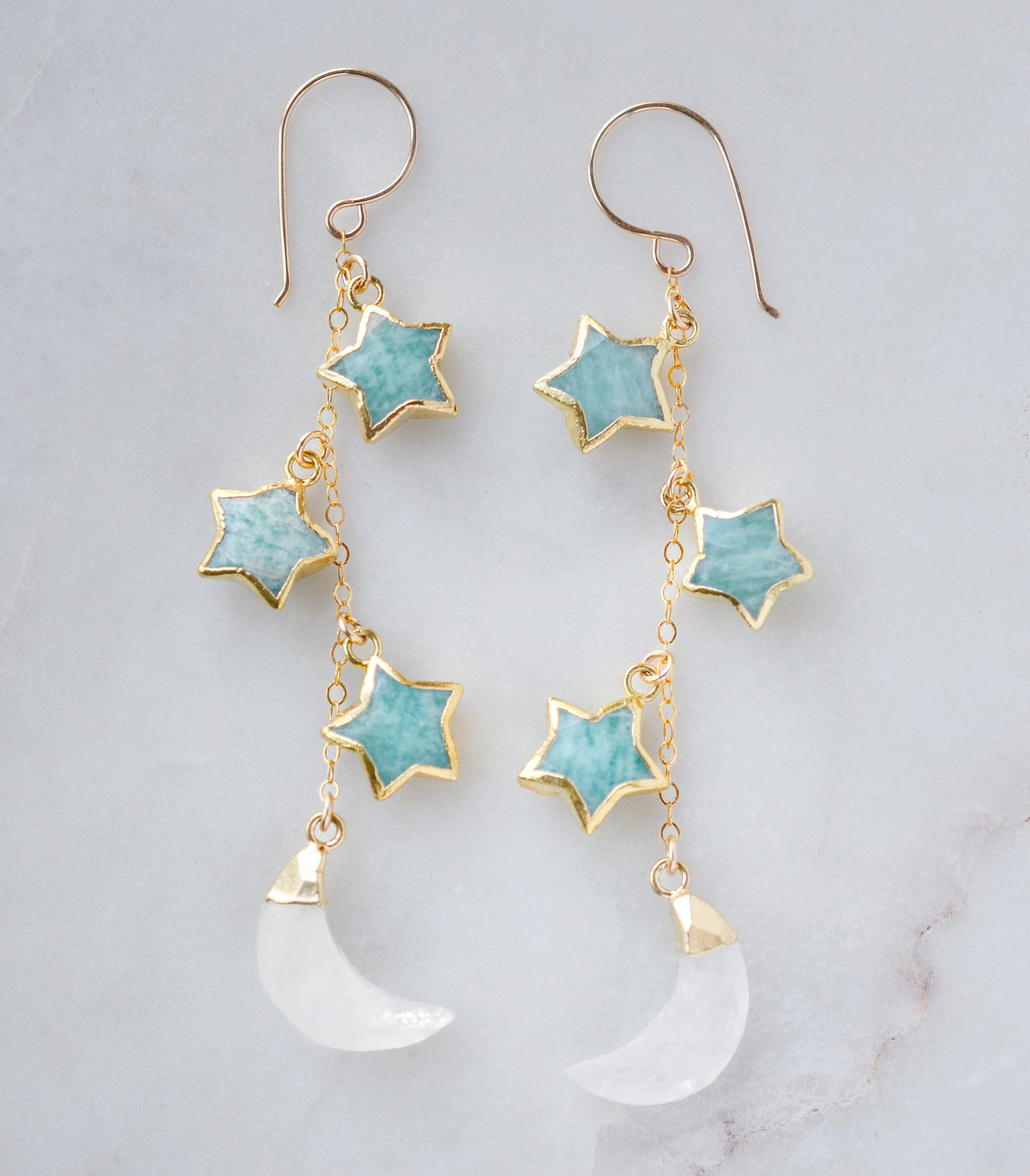 Blue amazonite star earrings in gold with rainbow moonstone crescents. Each earring has three gemstone stars and one moon dangling from it.