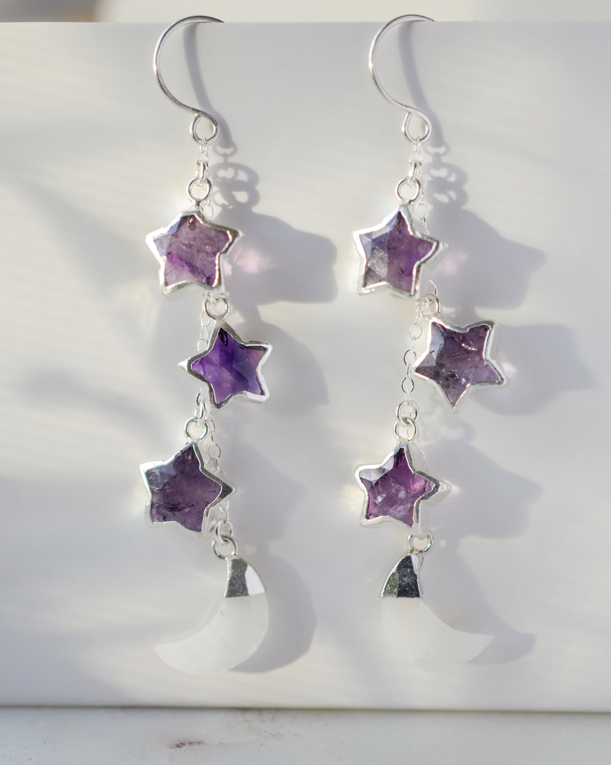 Three natural purple amethyst gemstone stars dangle atop rainbow moonstone crescent moons in these earrings. Shown in sterling silver.