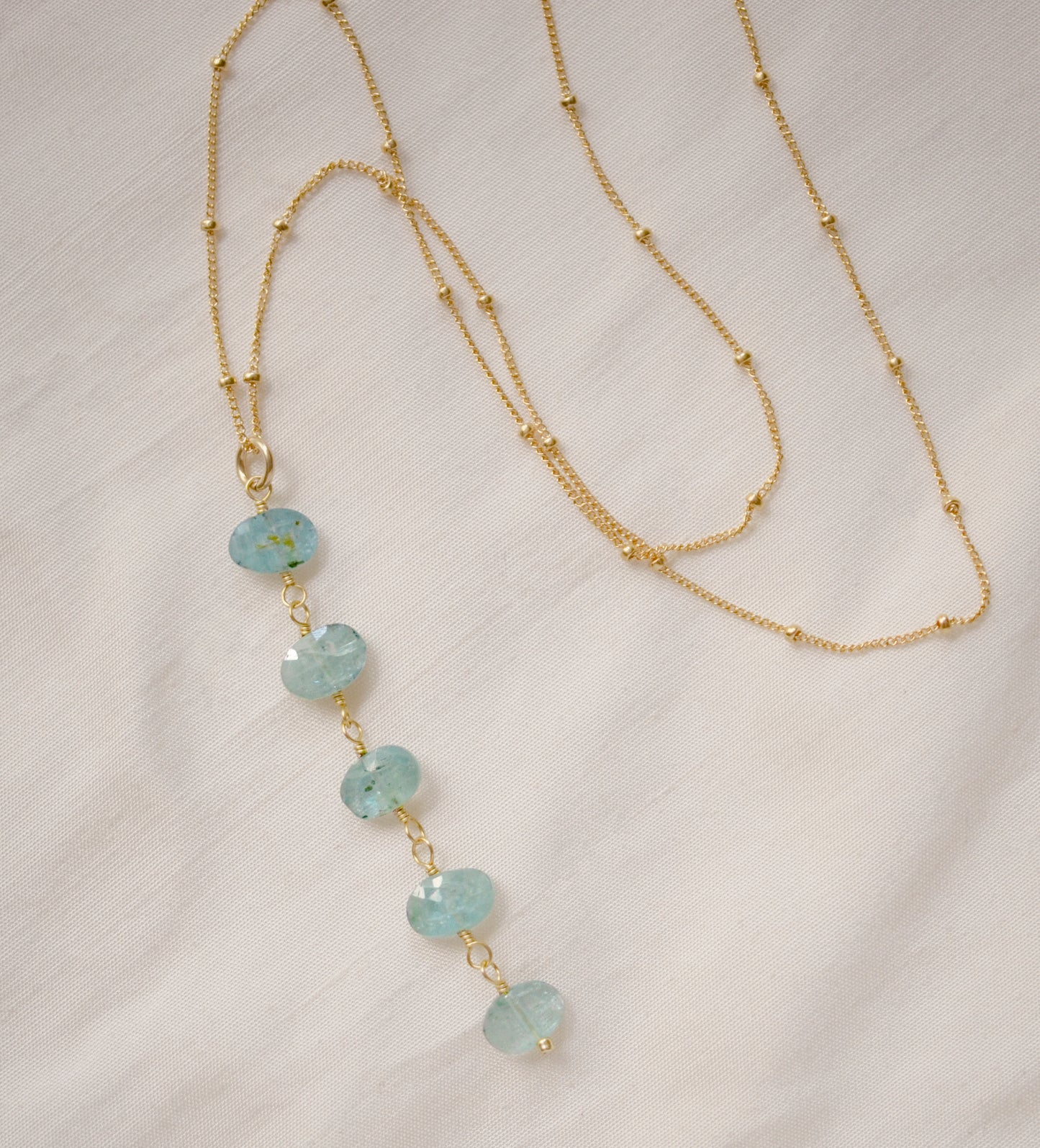 Genuine aqua blue Apatite gemstones set onto a beaded gold chain.