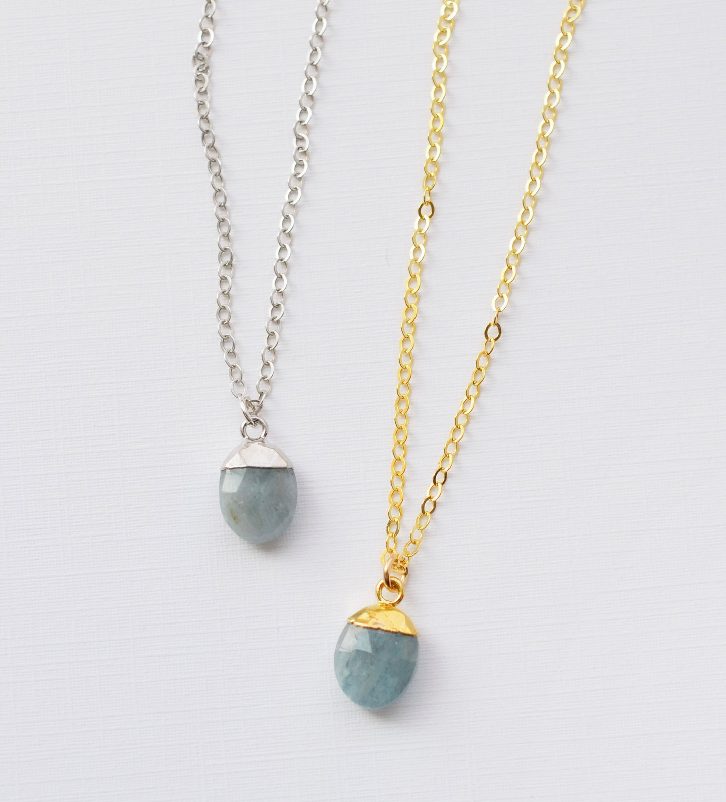 A 14k gold filled and sterling silver real aquamarine gemstone necklaces shown side by side. The jewelry is handmade in Connecticut, USA by Gemnia.