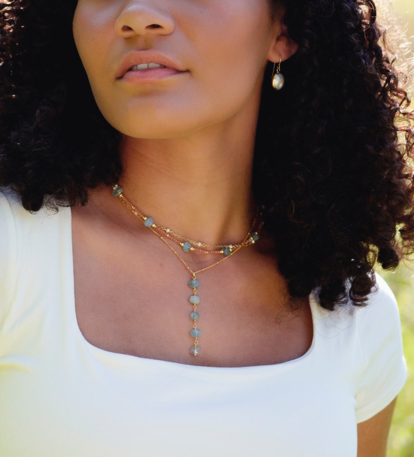 Modeled images. Pearl, aquamarine, and sunstone necklaces layered together.